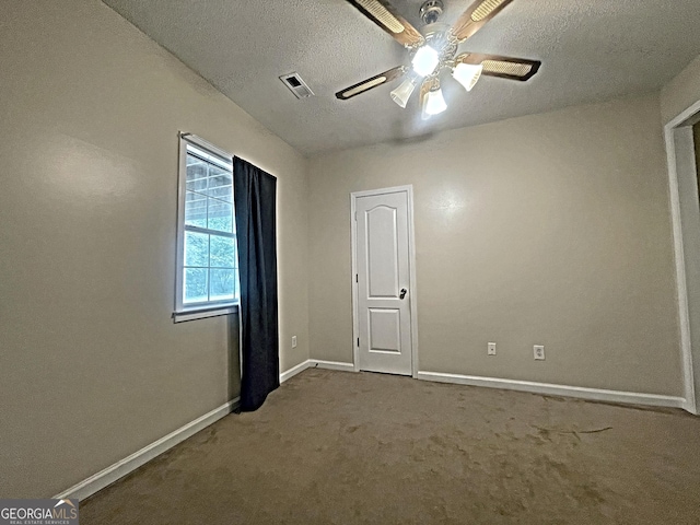 carpeted spare room featuring visible vents, ceiling fan, a textured ceiling, and baseboards