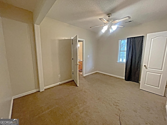 unfurnished bedroom with baseboards, visible vents, light colored carpet, ceiling fan, and a textured ceiling