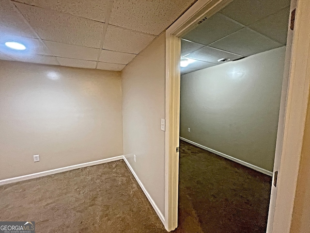 finished basement featuring baseboards, dark carpet, and a drop ceiling