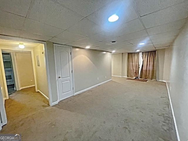 finished below grade area featuring carpet floors, a drop ceiling, and baseboards