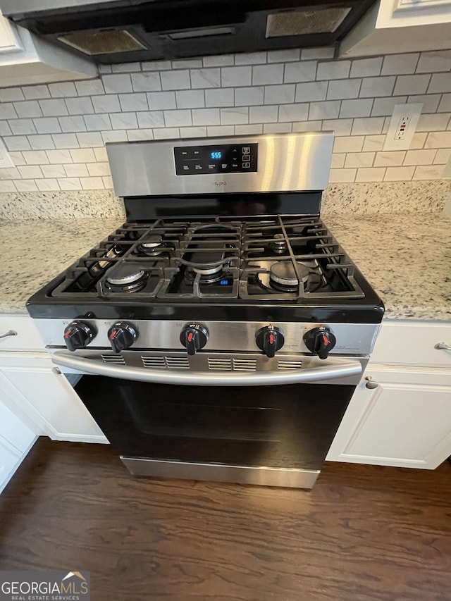 room details with light stone counters, tasteful backsplash, stainless steel range oven, and white cabinets