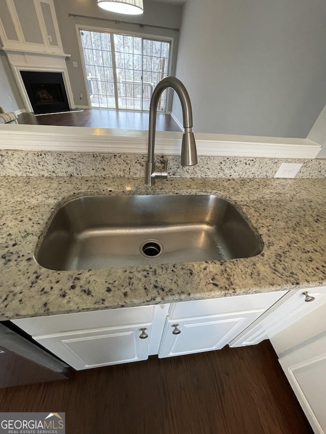 room details with light stone countertops, sink, and white cabinets