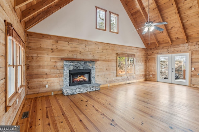 unfurnished living room with light hardwood / wood-style flooring, beam ceiling, a fireplace, and wood walls