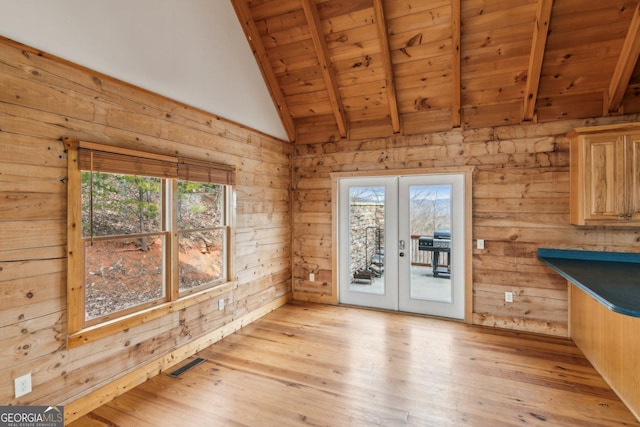 unfurnished dining area featuring wood ceiling, light hardwood / wood-style flooring, lofted ceiling with beams, french doors, and wood walls