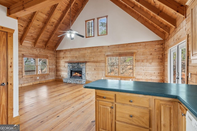 kitchen featuring beamed ceiling, a stone fireplace, dishwasher, and wooden ceiling