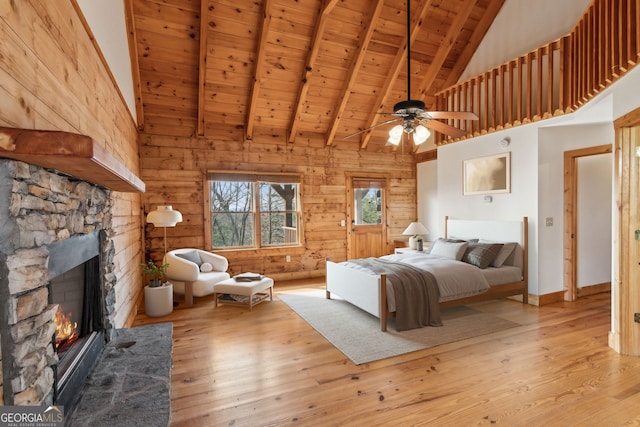 bedroom featuring a fireplace, wood walls, lofted ceiling with beams, wood ceiling, and light wood-type flooring