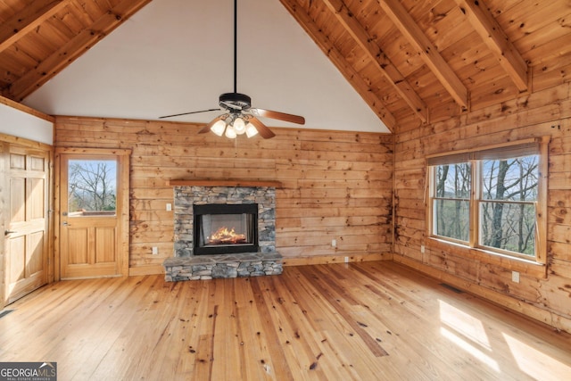 unfurnished living room featuring beam ceiling, wooden ceiling, wooden walls, and light hardwood / wood-style flooring