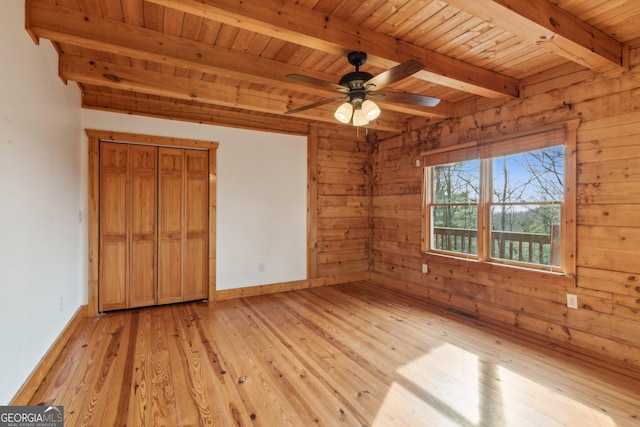 unfurnished bedroom featuring beam ceiling, light hardwood / wood-style flooring, wooden ceiling, and wooden walls