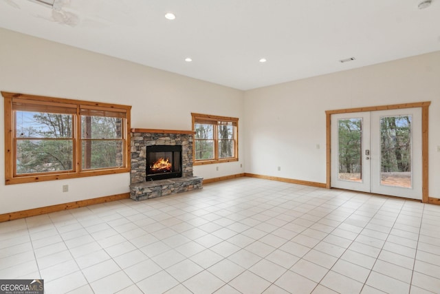 unfurnished living room featuring french doors, a fireplace, and light tile patterned floors