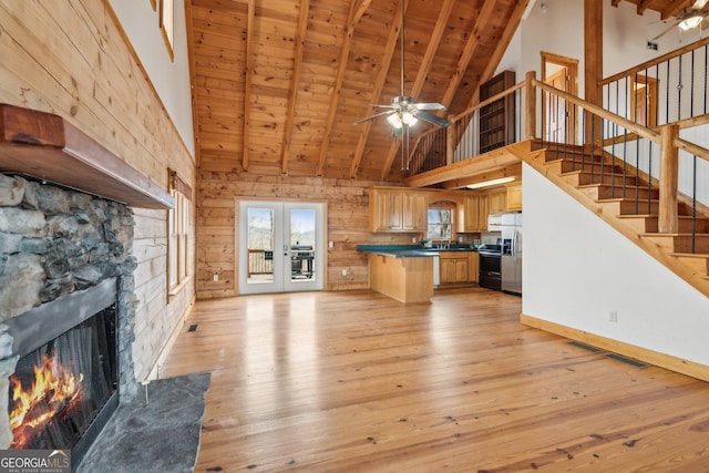 kitchen with a stone fireplace, wood ceiling, light hardwood / wood-style flooring, beamed ceiling, and stainless steel appliances