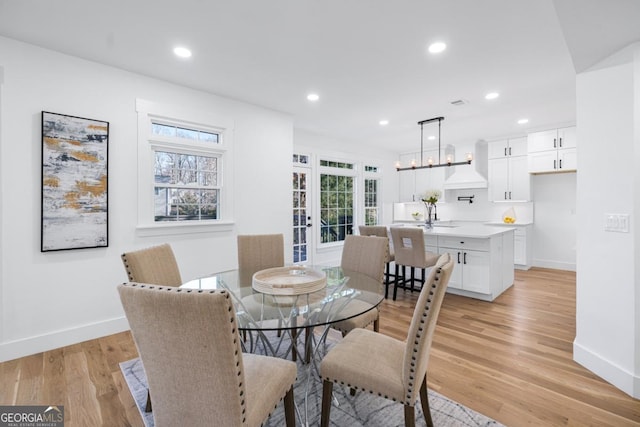 dining room with french doors, a healthy amount of sunlight, a chandelier, and light hardwood / wood-style flooring