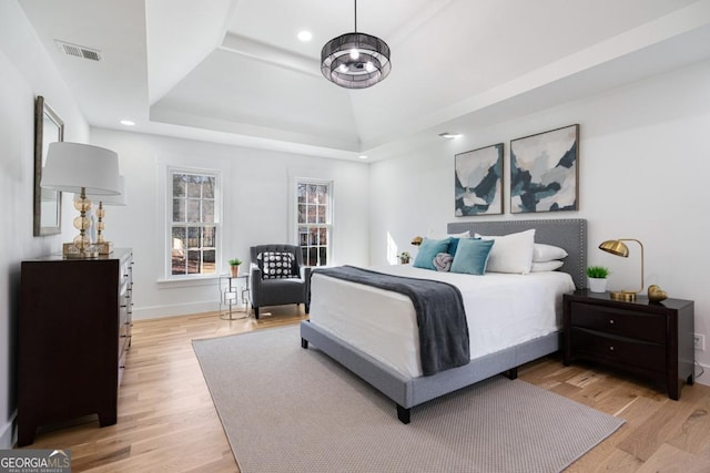 bedroom featuring a tray ceiling and light hardwood / wood-style floors