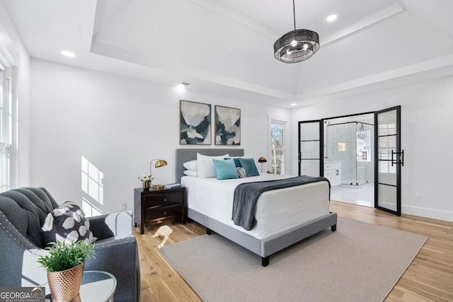 bedroom with a tray ceiling and light wood-type flooring