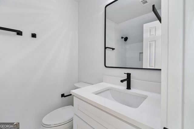 bathroom with vanity, walk in shower, and toilet