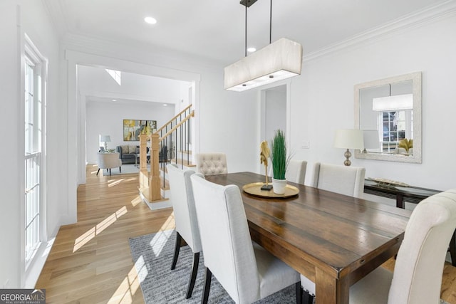 dining room with crown molding, a healthy amount of sunlight, and light hardwood / wood-style floors