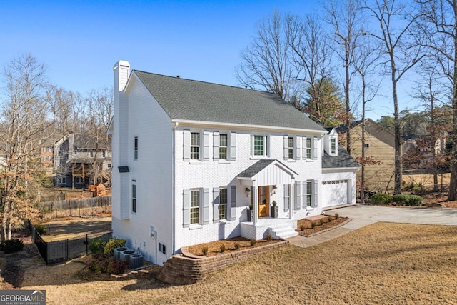 view of front of home featuring cooling unit, a garage, and a front lawn