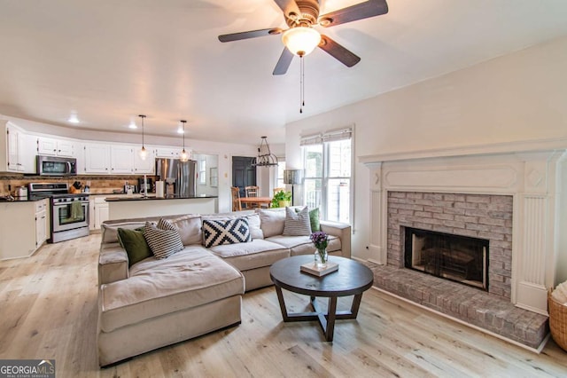 4222 Honey Creek Way, Powder Springs, GA 30127 - living area with light wood finished floors, a brick fireplace, and a ceiling fan