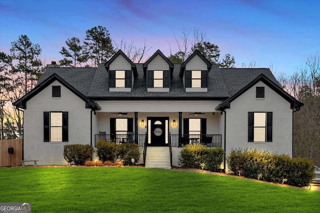 cape cod house with a lawn, ceiling fan, and covered porch