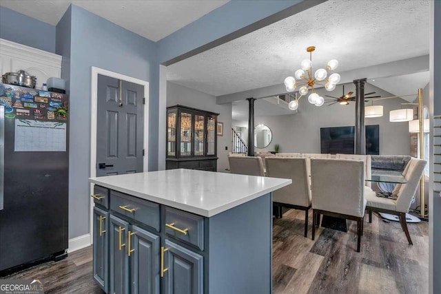 kitchen featuring stainless steel fridge, blue cabinetry, hanging light fixtures, dark hardwood / wood-style floors, and a center island