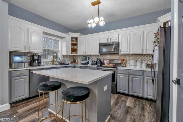 kitchen featuring a kitchen island, white cabinetry, dark hardwood / wood-style flooring, hanging light fixtures, and stainless steel appliances