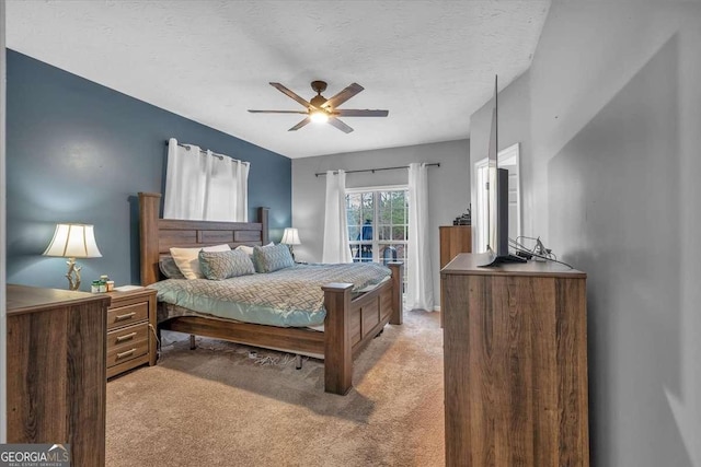 bedroom featuring ceiling fan, light colored carpet, and a textured ceiling