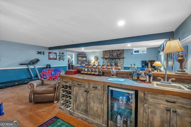 bar with sink, beam ceiling, light hardwood / wood-style flooring, and beverage cooler