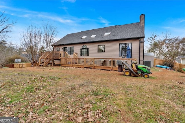 rear view of property with a deck and a lawn