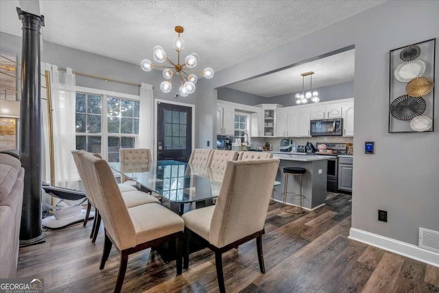 dining room featuring an inviting chandelier, dark hardwood / wood-style floors, sink, and a textured ceiling