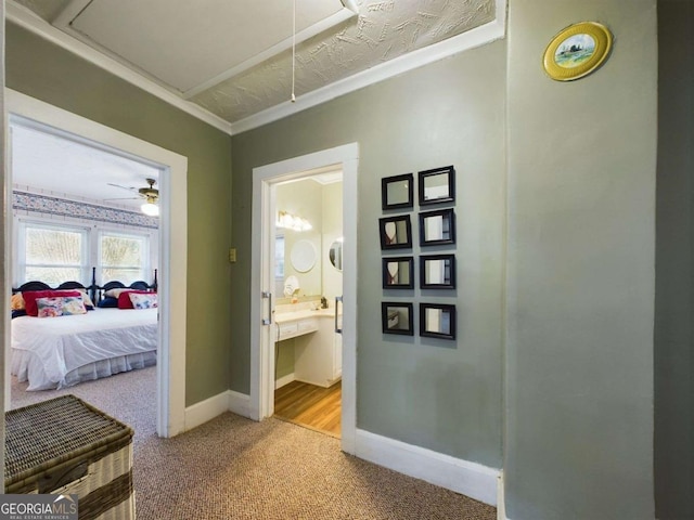 hallway featuring ornamental molding and light carpet