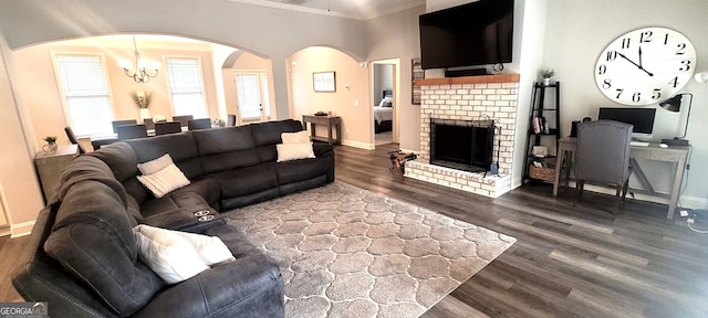 living room featuring crown molding, dark wood-type flooring, a fireplace, and a chandelier