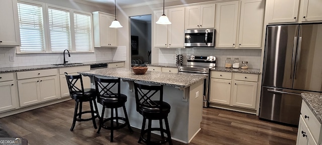 kitchen featuring stainless steel appliances, light stone countertops, a breakfast bar, and decorative light fixtures