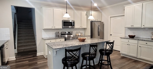 kitchen featuring pendant lighting, appliances with stainless steel finishes, light stone counters, white cabinets, and a kitchen bar