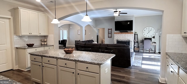 kitchen featuring decorative light fixtures, white cabinetry, a center island, ceiling fan, and dark wood-type flooring