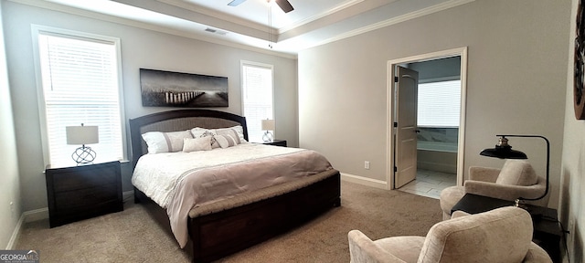 carpeted bedroom featuring crown molding, connected bathroom, ceiling fan, and a tray ceiling