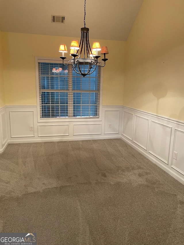 spare room featuring carpet and an inviting chandelier