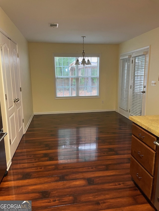 unfurnished dining area with dark hardwood / wood-style floors and a notable chandelier