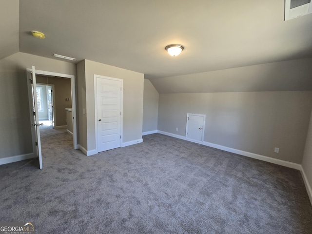 additional living space featuring lofted ceiling and dark colored carpet