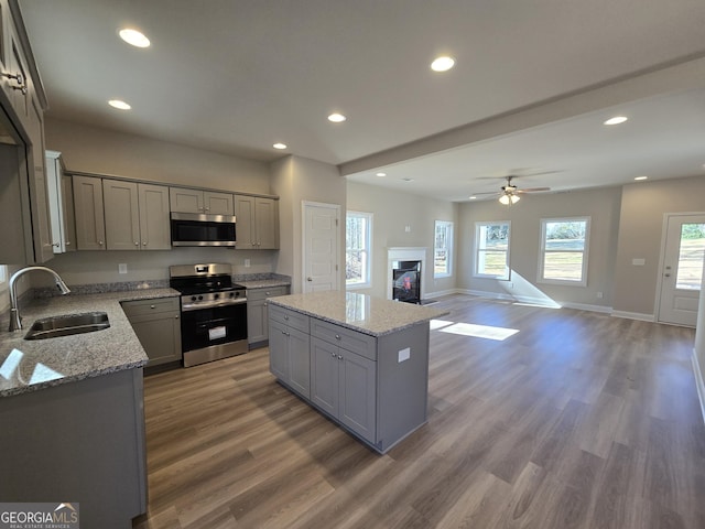 kitchen featuring sink, gray cabinets, stainless steel appliances, a center island, and light stone countertops