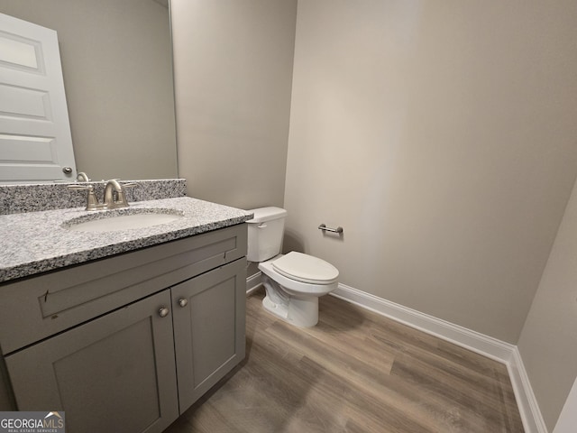 bathroom with wood-type flooring, vanity, and toilet