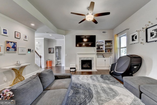 living room featuring hardwood / wood-style flooring, ceiling fan, ornamental molding, and a premium fireplace