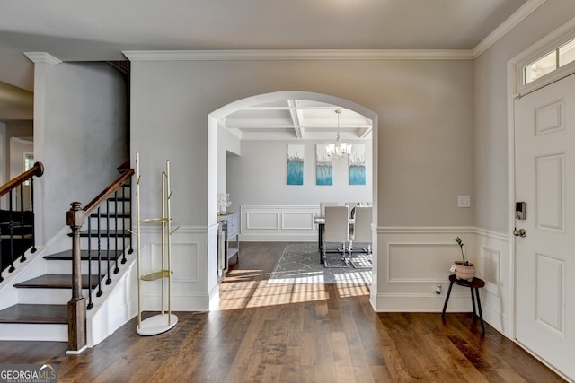 foyer entrance featuring an inviting chandelier, coffered ceiling, crown molding, dark wood-type flooring, and beam ceiling