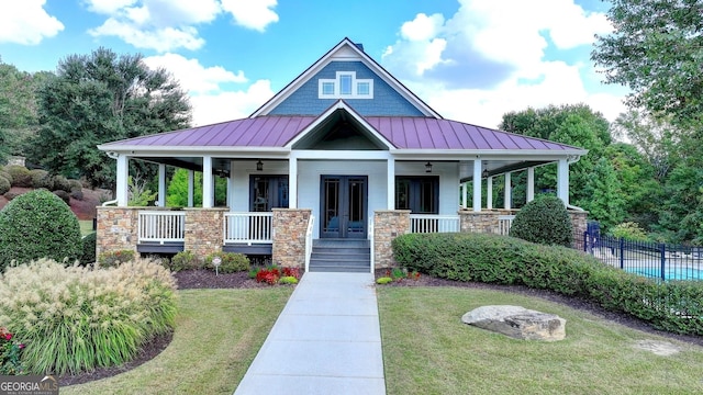 view of front of house with a porch, a front lawn, and french doors