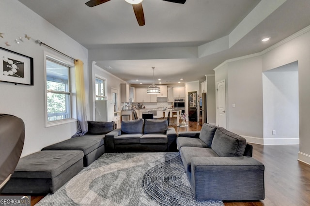 living room featuring hardwood / wood-style flooring, ornamental molding, and ceiling fan