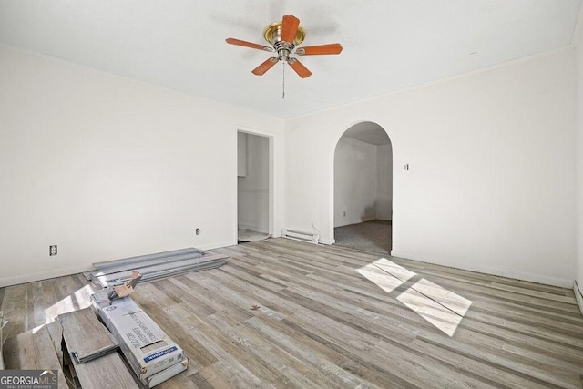 spare room with baseboard heating, ceiling fan, and light wood-type flooring