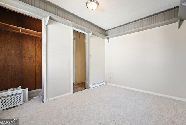 unfurnished bedroom with carpet flooring, a closet, and a baseboard heating unit