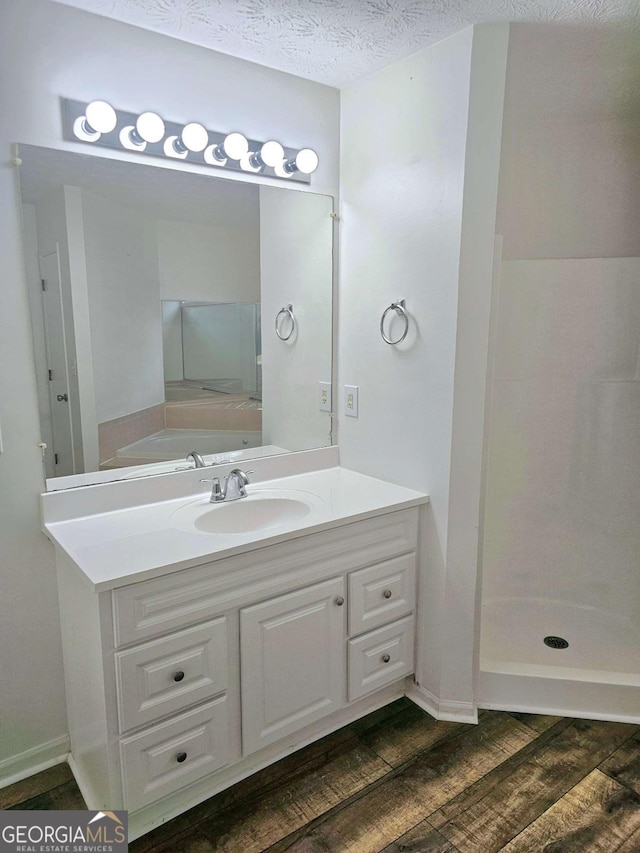 bathroom featuring vanity, hardwood / wood-style floors, a textured ceiling, and walk in shower