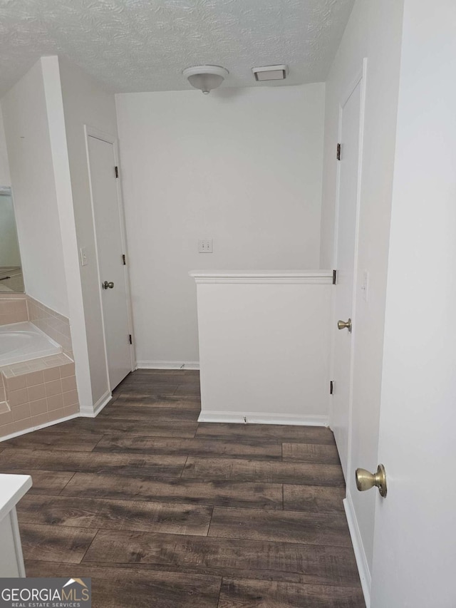 corridor with dark wood-type flooring and a textured ceiling