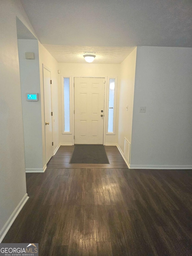 entryway with dark wood-type flooring and a textured ceiling