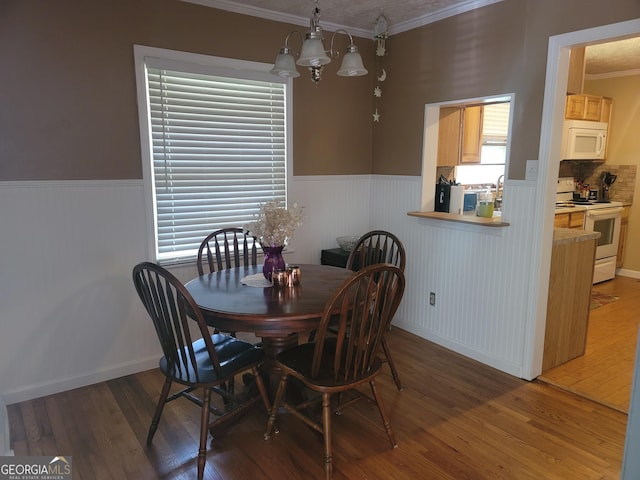 dining room with crown molding, plenty of natural light, dark hardwood / wood-style floors, and an inviting chandelier