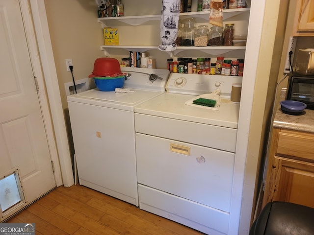 clothes washing area with independent washer and dryer and light wood-type flooring